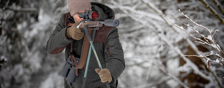 Jäger im Winterwald mit Gewehr im Anschlag