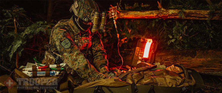 Soldat verpflegt Verwundeten in der Nacht mit XPLight Rotlicht