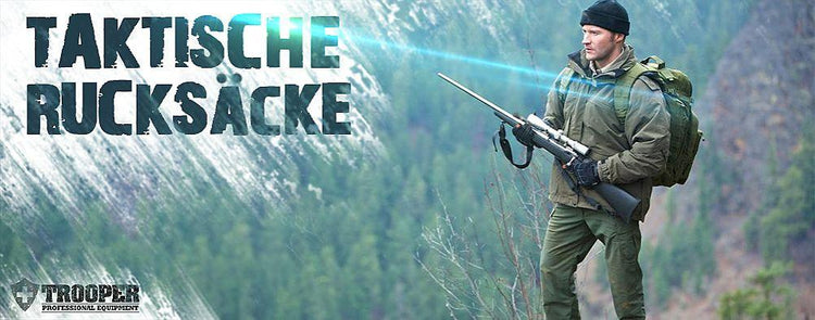 Jäger mit taktischem Rucksack und Gewehr im Bergwald