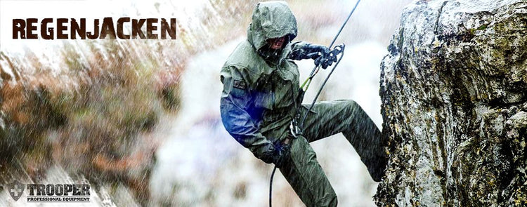 Mann, der sich gekleidet in einer Regenjacke an einer Steinwand abseilt
