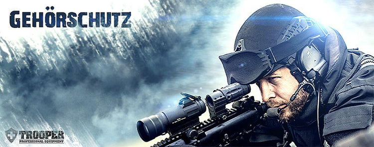 Ein Mann mit einer Schusswaffe in der Hand und einem Helm mit integriertem Gehörschutz auf dem Kopf.